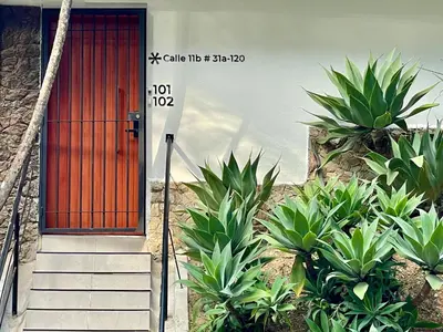 a red door on a building with some plants at Apartments with Jacuzzi in El Poblado by Wynwood House in Medellín