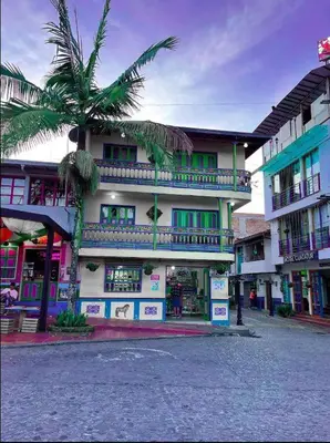 a building with a palm tree in front of it at Apartamento Parque de Guatapé in Guatapé