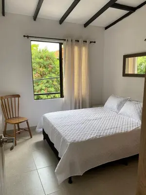 a bedroom with a bed and a chair and a window at Hermoso Apartamento en Medellín in Medellín