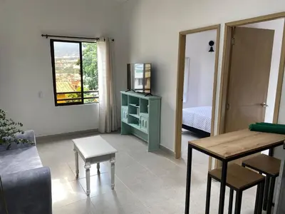 a living room with a television and a table and chairs at Hermoso Apartamento en Medellín in Medellín