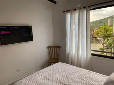 a bedroom with a bed and a window and a chair at Hermoso Apartamento en Medellín in Medellín