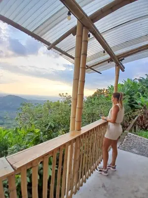 a woman standing on a balcony looking at her cell phone at Zioru cabaña in Belalcázar