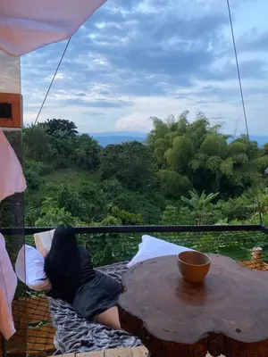 a woman sitting at a table looking out of a window at Turmequé cabaña in Alto de la Mina