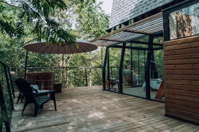 a wooden deck with a table and an umbrella at Silvery Bungalows en el Bosque in San Carlos