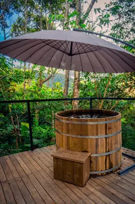 a wooden barrel with an umbrella on a deck at Silvery Bungalows en el Bosque in San Carlos