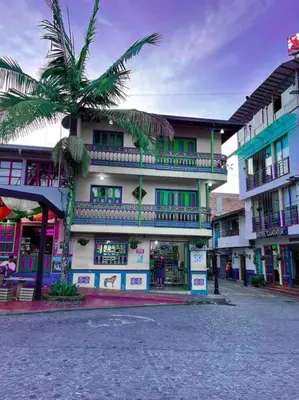 a building with a palm tree in front of it at Apartamento Parque Central Guatapé in Guatapé