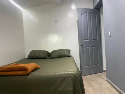 a bedroom with a bed with a green blanket and a blue door at The oasis apartamento de 3 alcobas Laurles estadio LA70 in Medellín
