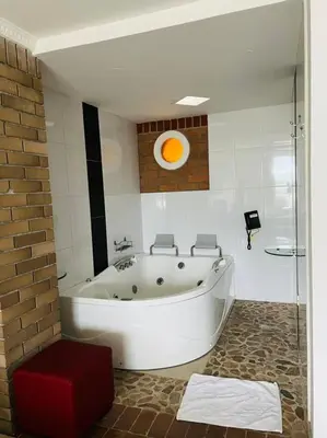 a white bath tub in a bathroom with a red stool at HOTEL MONTERREY in Ruiosucio