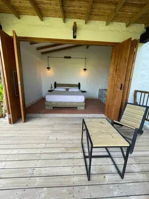 a bedroom with a bed and two chairs on a porch at Finca Hotel el Valhalla in Doradal