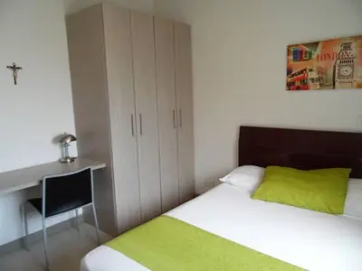 a bedroom with a bed with a desk and a green pillow at Amoblados Medellin Estadio in Medellín