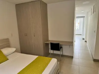 a bedroom with a bed and a desk and a chair at Amoblados Medellin Estadio in Medellín