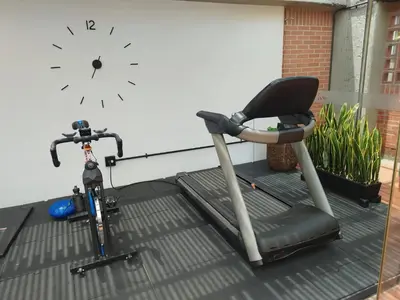 a bike and a treadmill next to a wall with a clock at Orange Suites by Vibra Bonita in Medellín