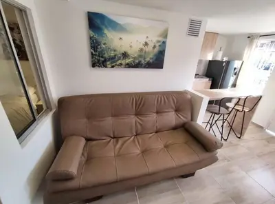 a brown couch in a living room with a kitchen at Apartaestudio S101 a 2 calles de Milán Urbanevo in Manizales