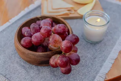 a wooden bowl of grapes next to a candle at Shabbat Hotel Boutique in San Vicente