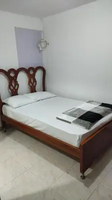 a bed with a wooden frame and white sheets at Habitación con baño privado#5 in Medellín