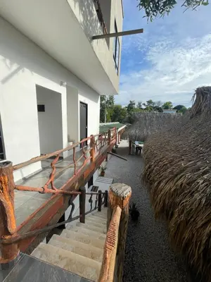 a porch of a building with stairs and a thatch roof at finca campestre las heliconias in Puerto Triunfo