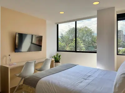 a bedroom with a bed and a desk with a tv at Oliving by Wynwood House in Medellín
