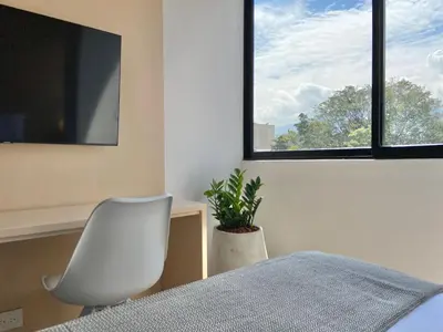 a bedroom with a white chair and a window at Oliving by Wynwood House in Medellín