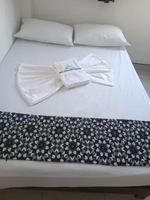 a bed with white sheets and two towels on it at HOTEL NORCASIA RIOS Y AVENTURAS in Norcasia