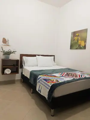 a bedroom with a bed and a table with a picture at Volarte Hotel in Jardin