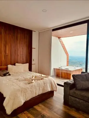 a bedroom with a bed and a large window with a tub at Montecielo Hosting in Guatapé