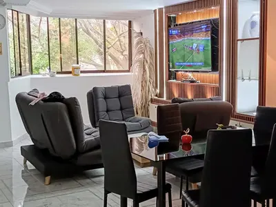 a waiting room with chairs and a table and a tv at cool de laureles Medellín in Medellín