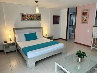 a bedroom with a large bed and a table at Amoblados Medellin Poblado Patio Bonito in Medellín