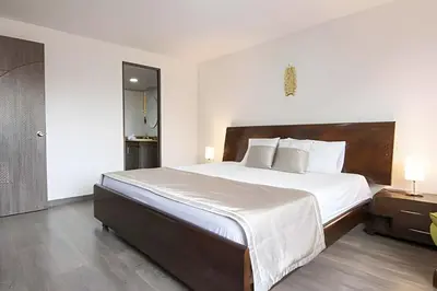 a bedroom with a large bed with white sheets and pillows at Vistas Top | Parking | Cerca De Estadio y 