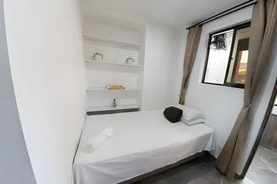 a small bedroom with a white bed and a window at Vistas Top | Parking | Cerca De Estadio y 