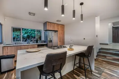 a kitchen with a large white counter and chairs at Poblado Mansion With Hot Tub & A/C Sleeps 9 in Medellín