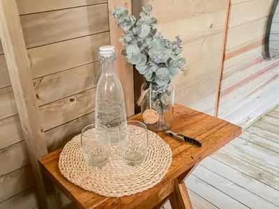 a table with glasses and a bottle and a vase at Rùstico Glamping in Santa Elena