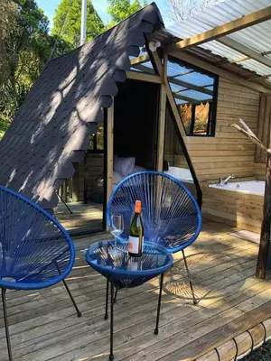 two blue chairs and a bottle of wine on a deck at Rùstico Glamping in Santa Elena