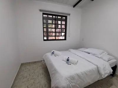 a white bedroom with a bed with towels on it at Hermosa finca a 5 minutos aeropuerto in Guarne