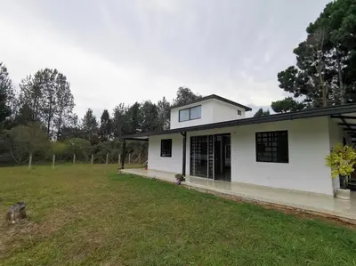 a white house with a large yard in front of it at Hermosa finca a 5 minutos aeropuerto in Guarne