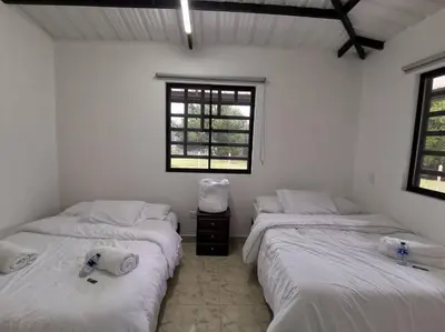 two beds in a room with white walls and windows at Hermosa finca a 5 minutos aeropuerto in Guarne