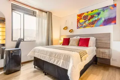 a bedroom with a large bed and a painting on the wall at Apartamento Lujoso cerca del Estadio Piso 6to in Medellín