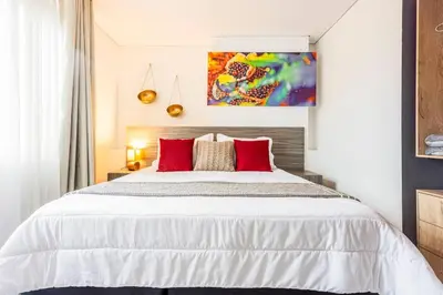 a bedroom with a large white bed with red pillows at Apartamento Lujoso cerca del Estadio Piso 6to in Medellín