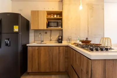 a kitchen with wooden cabinets and a black refrigerator at Apartamento Lujoso cerca del Estadio Piso 6to in Medellín