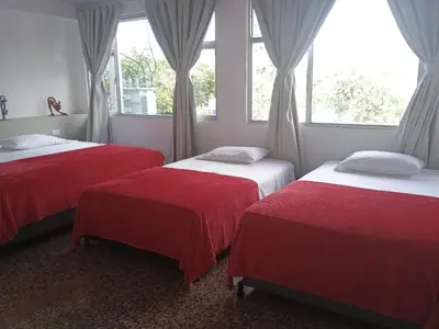 two beds in a room with two windows at HOTEL GANADERO in La Dorada
