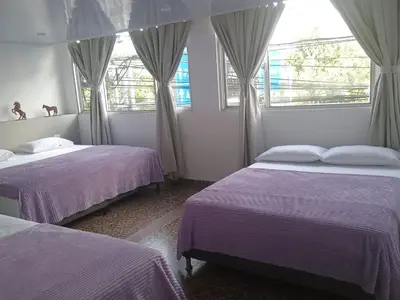 a bedroom with two beds and two windows at HOTEL GANADERO in La Dorada