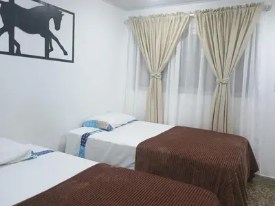 a bedroom with two beds and a picture of a horse on the window at HOTEL GANADERO in La Dorada