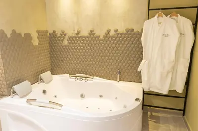 a bathroom with a white bath tub and a robe at Sonata 44 Hotel Laureles in Medellín