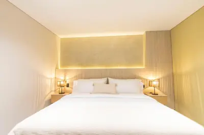 a bedroom with a large white bed with two lamps at Sonata 44 Hotel Laureles in Medellín
