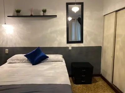 a bedroom with a bed with a blue pillow and a mirror at hostal casa prado in in Medellín