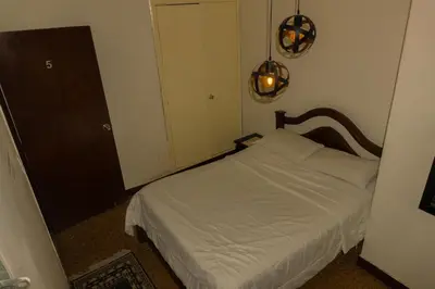 a small bedroom with a white bed and two lights at hostal casa prado in in Medellín