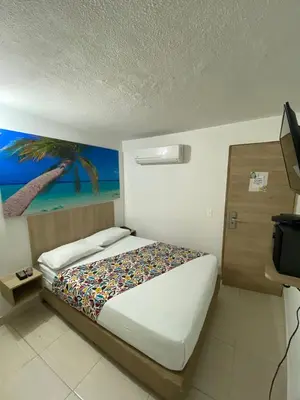 a bedroom with a bed and a painting of a palm tree at Hotel Suites 44 Laureles in Medellín