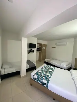 a bedroom with two beds and a tv in it at Hotel Suites 44 Laureles in Medellín