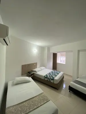 a bedroom with two beds and a tv in it at Hotel Suites 44 Laureles in Medellín