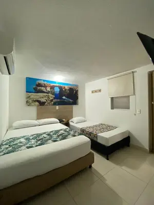 a bedroom with two beds and a painting on the wall at Hotel Suites 44 Laureles in Medellín