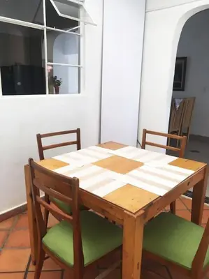 a wooden table with two chairs and a table and a window at Casa zona Laureles in Medellín